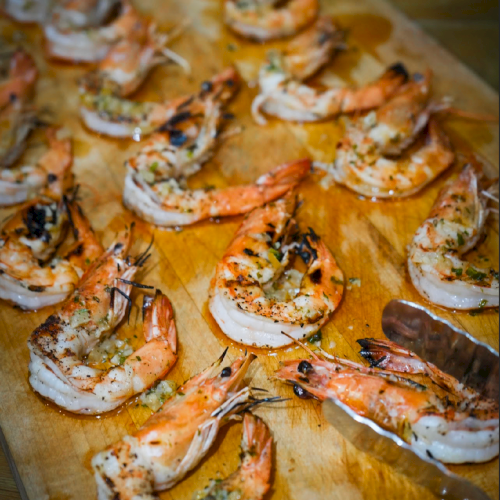 Grilled prawns seasoned with herbs and spices arranged on a wooden board, ready to serve as a tasty seafood dish.