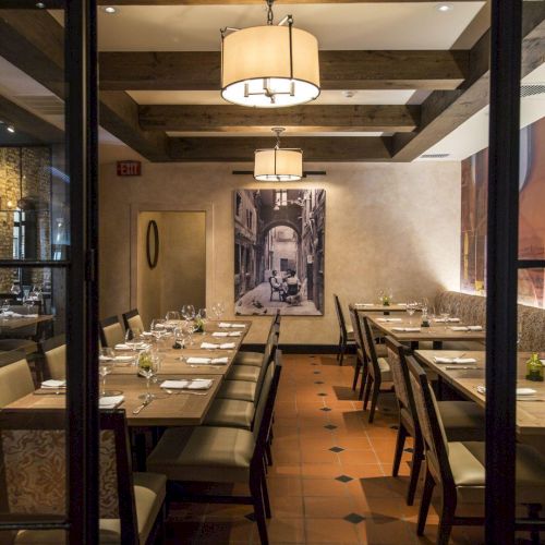 The image shows a cozy restaurant interior with wooden tables and chairs, warm lighting, and artwork on the walls.