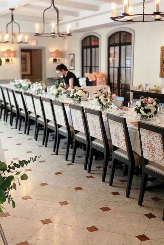 A long dining table setup for a wedding reception with a sign reading &ldquo;the night before&rdquo; and floral centerpieces along the table.