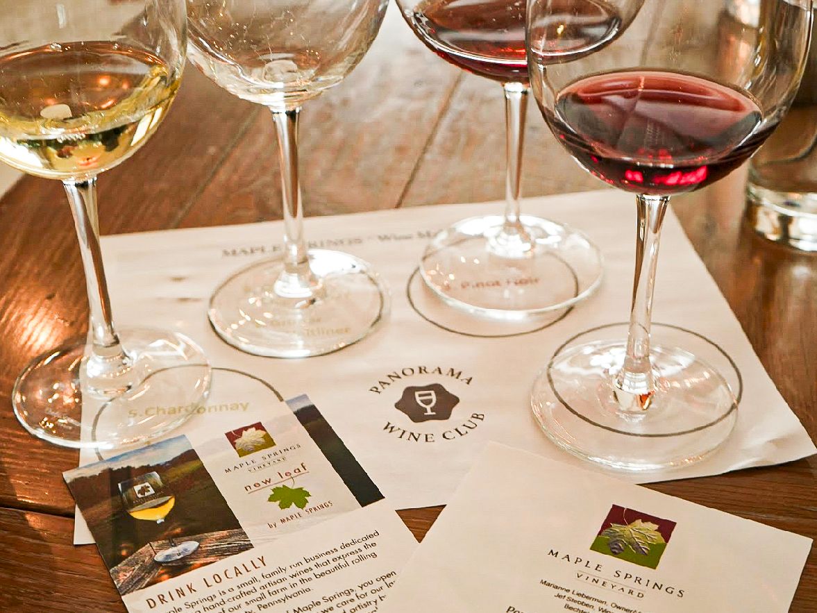 A wine-tasting setup with multiple glasses, tasting notes, and cards on a wooden table, inviting sip-by-sip exploration.