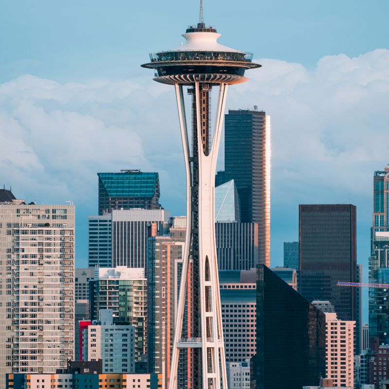 The image shows the Space Needle towering over the Seattle skyline with various skyscrapers in the background.