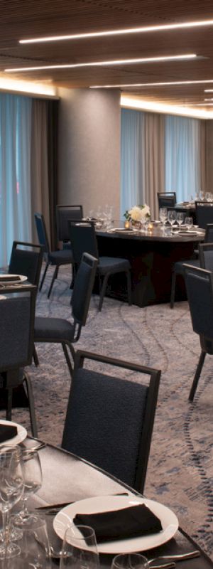 A banquet hall is set up with round tables, elegant table settings, and soft lighting, creating a sophisticated ambience.